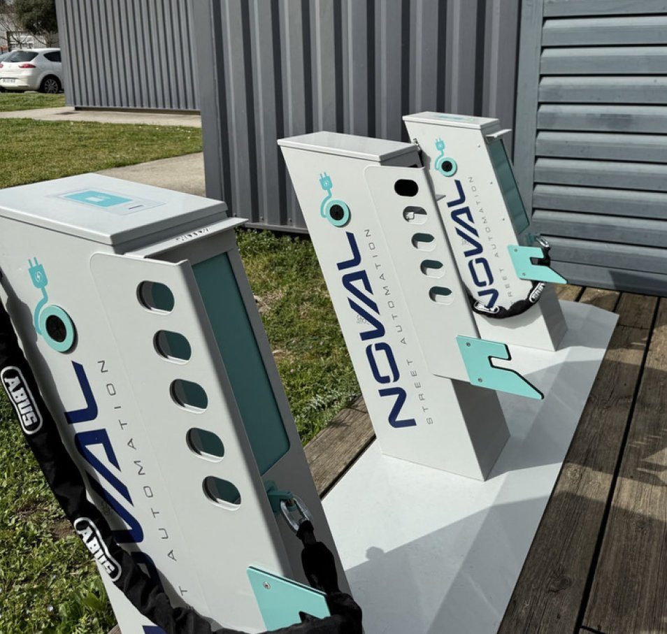 Trois bornes CYPARK NOVAL installées en extérieur avec chaîne antivol ABUS — stationnement vélo sécurisé